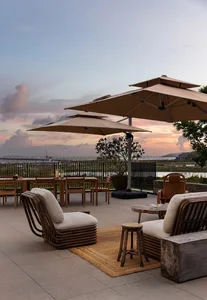 A relaxed outdoor patio with wicker chairs, dining tables, and umbrellas, perfect for dining or socializing