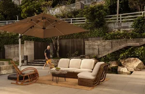 Outdoor living space with a wicker couch, chair, and dining table, surrounded by a potted plant and decorative vase