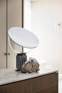 A clean bathroom with a sink, toilet, and large white light fixture, accompanied by two rocks on the countertop