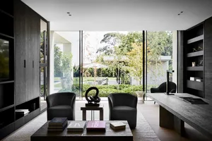 A modern living room with two chairs, a coffee table, and several books, featuring a well-lit and inviting atmosphere