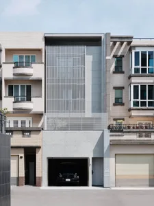 A modern building with a prominent glass wall, surrounded by windows and balconies, set against a city backdrop