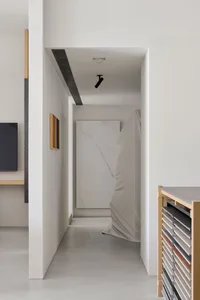一間現代客廳以白色色彩為主，掛在牆上的電視和沙發，透過窗戶流入自然光線