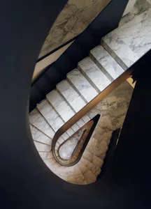 A black and white photograph of a curved marble staircase with a sophisticated and timeless appearance