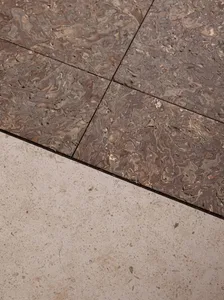 A modern living space with a tiled floor, featuring a combination of wood and stone materials, natural light, and a clean design