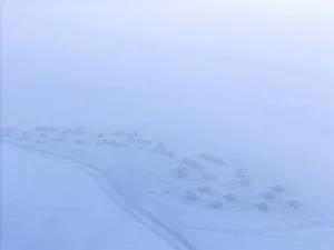 a row of small wooden cabins covered in snow in a vast winter landscape