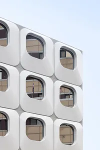 A large white building with a modern design, featuring a grid pattern of square windows and a predominantly white facade