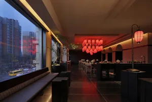 A modern restaurant with wooden tables, red lighting, and potted plants, creating a warm and inviting atmosphere