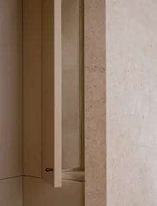 A dimly lit bathroom with a wooden door and a glass window, visible through the open door