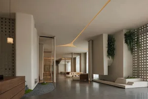 A modern living space with a white color scheme, a large couch, a chair, and a potted plant, well-lit with natural light and decorated with various furniture pieces