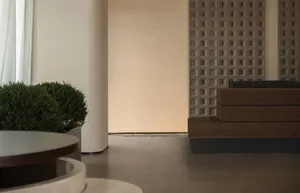 Cozy living space with a wooden floor, a white wall, a bench, and a potted plant