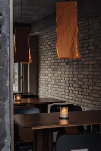 Dining area with tables, chairs, candles, and brick walls, creating a warm and inviting atmosphere