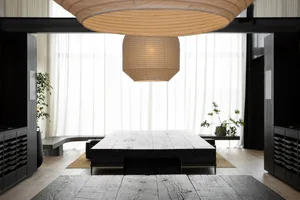A well-lit living room with a black table and couch, featuring a large hanging light and modern decor