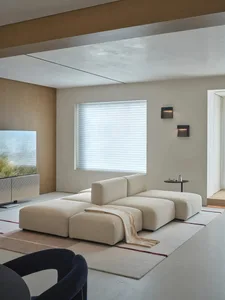 A well-lit living room with a white couch, a blanket, and a window in the background