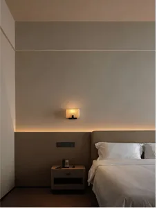 A well-lit bedroom with a wooden bed frame, nightstand, and lamp, creating a warm and inviting atmosphere
