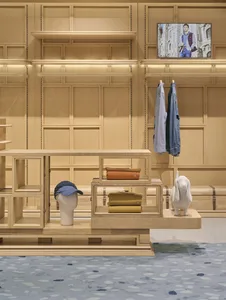 A modern store display featuring a wooden shelf with neatly arranged clothing items and accessories, set against a soft and inviting background