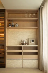 A modern kitchen with wooden cabinets and shelves, filled with various items, and well-lit for a warm atmosphere
