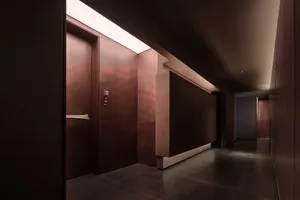 A dimly lit hallway with a doorway and a wooden wall, featuring a simple and functional design