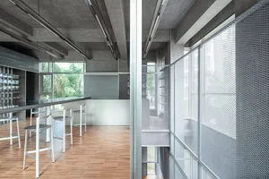 Large open room with concrete and wood elements, furniture, and natural light from windows