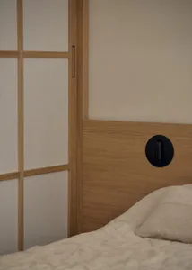 A well-lit bedroom with a wooden headboard, a white bed, and a wooden cabinet, creating a comfortable atmosphere