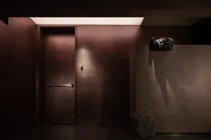 A dimly lit wooden hallway with a doorway and cabinet, creating a moody atmosphere