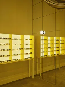 A colorful eyewear display with glasses in various styles and colors, set against a yellow background, with well-designed lighting creating a welcoming atmosphere
