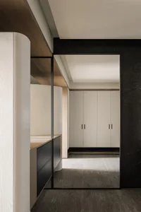Modern kitchen and hallway with black cabinets, white countertops, and natural light from the doorway
