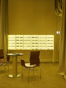 A store or showroom with a yellow wall and a display case filled with various pairs of glasses, arranged in an organized and visually appealing presentation