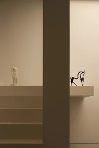 A dimly lit room with a statue on a pedestal in the center, surrounded by a museum or art gallery atmosphere