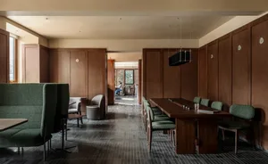 Dining area with a wooden floor, a dining table, chairs, a couch, and a window allowing natural light