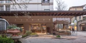 A city restaurant with a wooden facade, stone-like appearance, and a blend of traditional and modern elements, set against a city backdrop