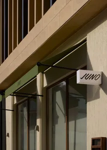 一間現代商店的前面有黑色遮陽棚，綠色裝飾，自然光從陽光中流入，創造出明亮和邀人的氣氛