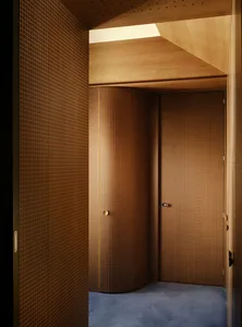 A dimly lit bathroom with a wooden door, open to reveal the interior of the room