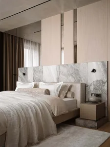 A modern bedroom with a bed, dresser, and marble headboard, featuring a neutral color palette and natural lighting