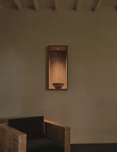 Cozy room with a wooden bench, a wooden bowl on a shelf, and a brown color scheme, lit by dim lighting