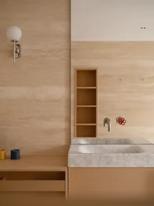 Bathroom with a white sink, wooden cabinet, and beige color scheme, lit by natural light