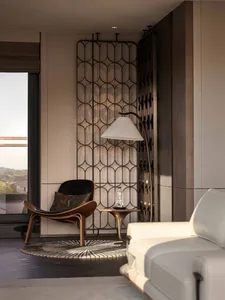 Cozy living room with a white couch and chair, a patterned wall, and a window with a view of the outdoors