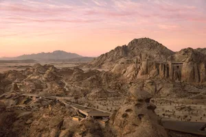 A serene natural landscape with a rocky terrain and a large rock formation, captured during sunset