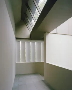 A calm and spacious lobby with a concrete wall and a large window allowing natural light to enter the space
