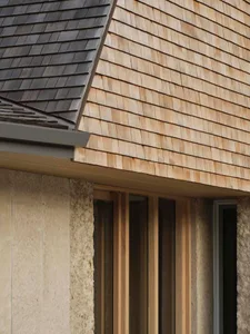 A beach house with a wooden roof, blending traditional and modern elements, featuring wood and stone accents, large windows, and a natural atmosphere