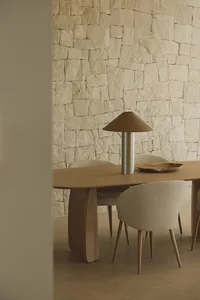 A modern dining room with a wooden table and chairs surrounded by a stone wall, well-lit and inviting