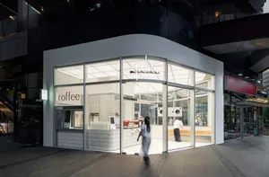 A casual coffee shop with a white exterior and glass door, well-lit and inviting