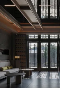 A bright and inviting living room with a white couch, a chair near a large window, and a wooden floor, allowing natural light to enter the space