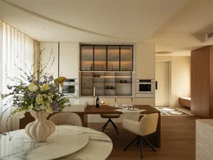 Modern kitchen with a wooden dining table, chairs, and a vase, surrounded by a refrigerator, oven, and microwave, with soft and warm lighting