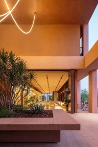 Inviting dining and lounge space with a pink exterior, multiple chairs, dining tables, a couch, and a warm color palette