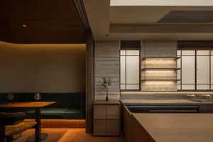 Modern kitchen with a wooden countertop, dining table, and potted plant, featuring a sink, refrigerator, and wine glass, with soft and warm lighting