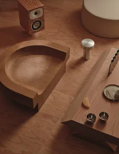 A simple bathroom with wooden floors and a wooden table, featuring a toilet, sink, and decorative bowl and cup