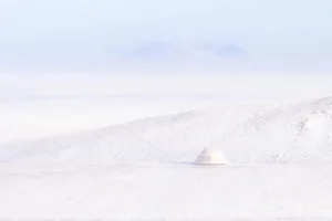 A dome-shaped structure stands out against a snowy backdrop, with a mix of white and grey material visible