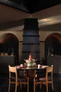 一間餐廳室,擺放桌子,椅子,黑色煙囪,杯子,碗,和花瓶,準備一頓用餐