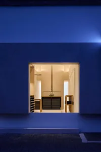 A modern kitchen with a blue wall, a window, and a sink and refrigerator, with dim lighting creating a cozy atmosphere