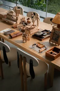 A wooden dining table with various items on it, surrounded by chairs, in a warm and inviting living room or dining area